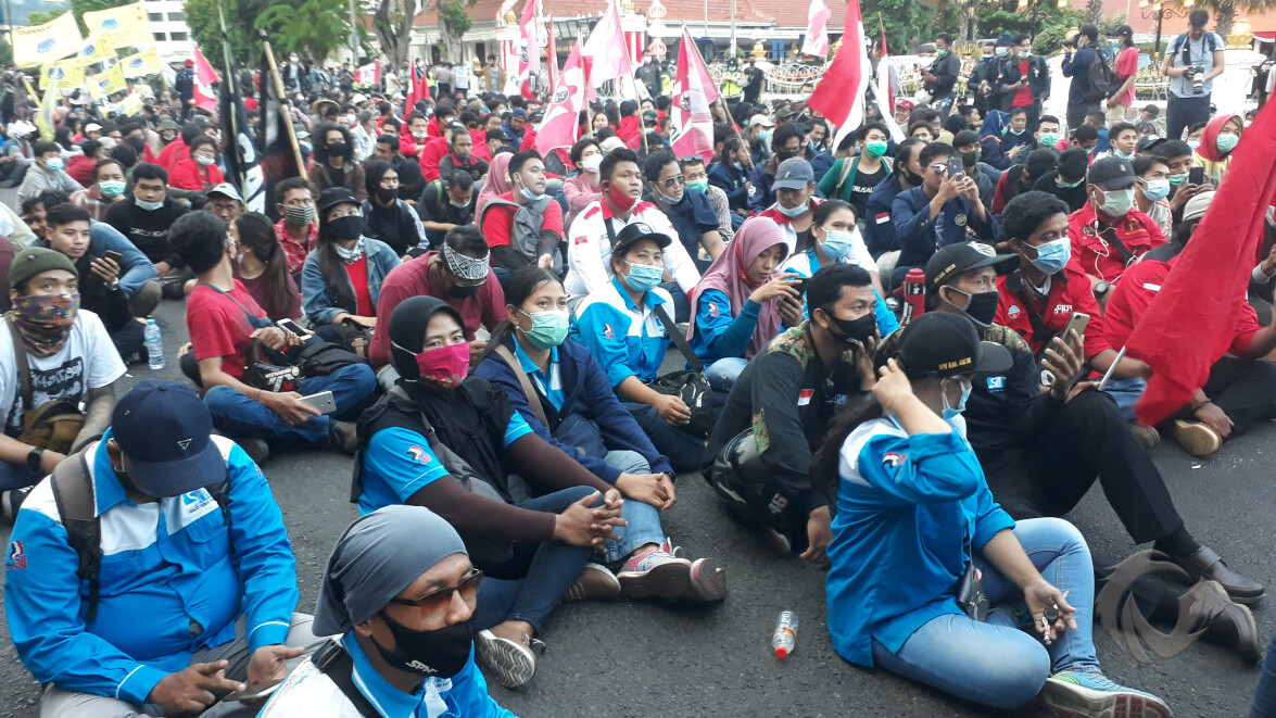 Peserta unjuk rasa gelar aksi duduk di Jalan Gubernur Suryo Grahadi Kota Surabaya, Selasa (20/10/2020).