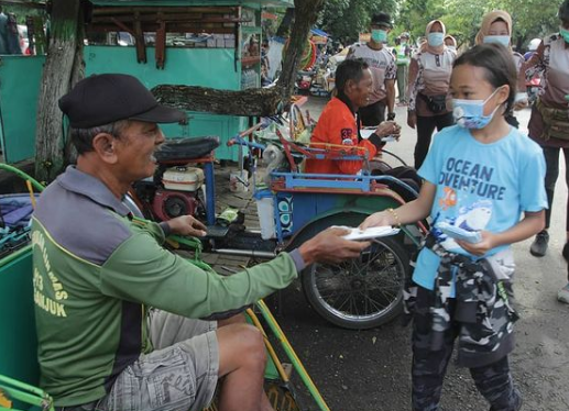 Salah satu anggota rombongan Dandim Nganjuk saat membagikan masker kepada warga, Jumat (18/12/2020).