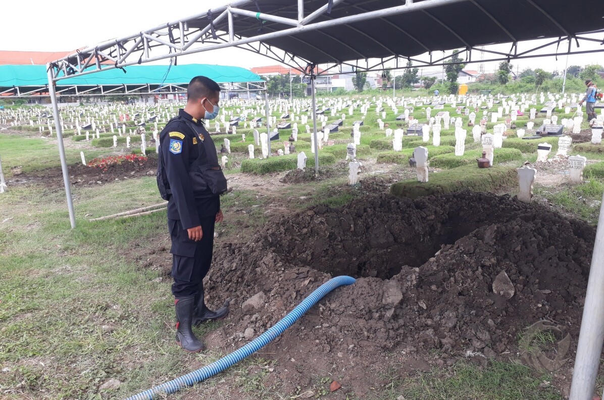 Liang kubur tempat jenazah Fadly Satrianto dimakamkan di TPU Keputih, Sukolilo, Kota Surabaya, Jumat (15/1/2021) dan Qafidz (23) anggota BPB Linmas sedang memeriksa galian.