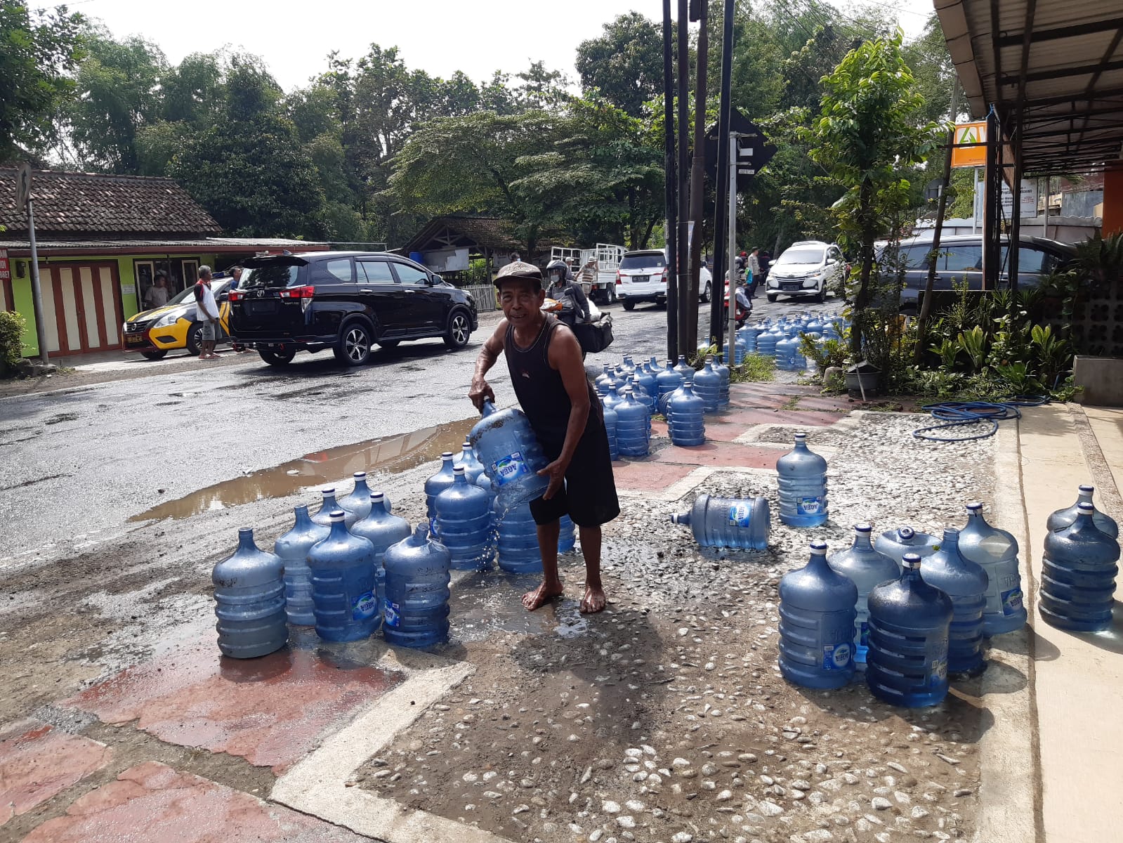 Warga mengumpulkan galon air mineral saat truk yang memuat galon terguling di Tulungagung, Senin (13/6/2022).